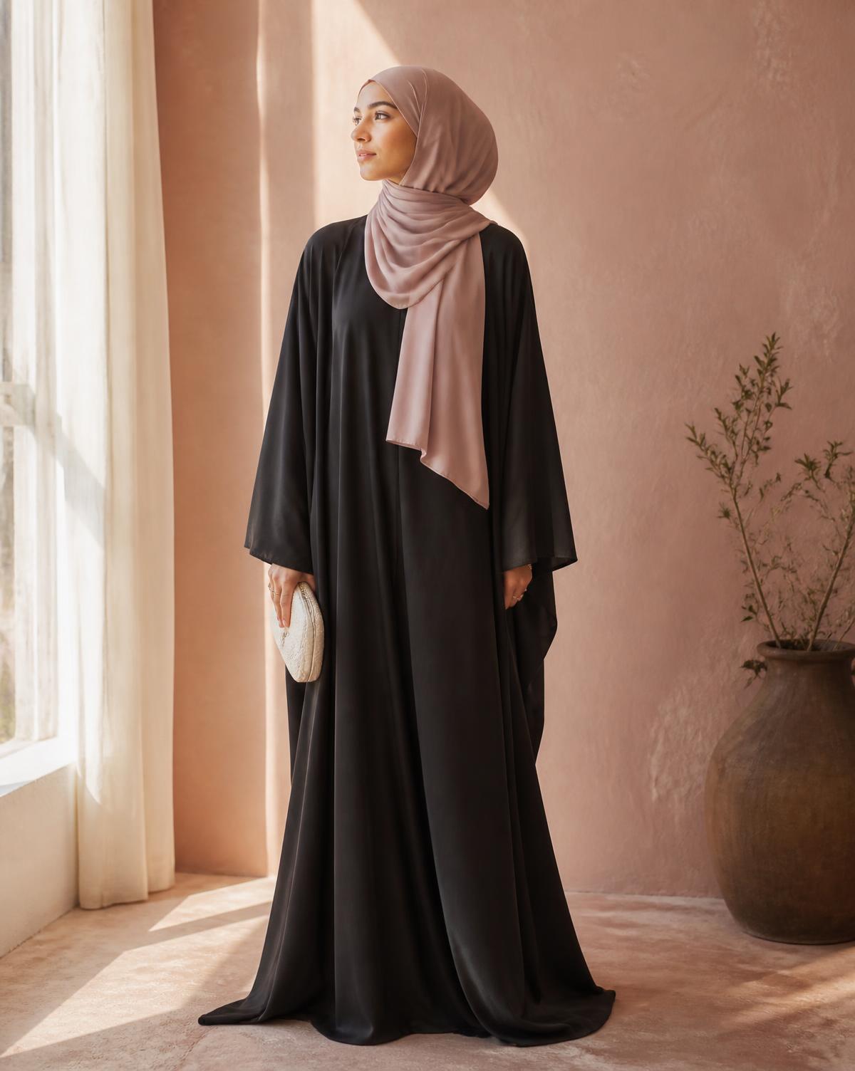 Woman wearing a charcoal abaya with a blush pink hijab